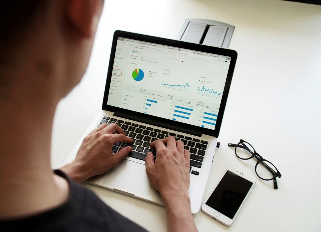 Person typing on a laptop while reviewing an analytics dashboard with charts