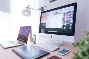 A desk with an iMac and laptop open, evaluating software on screen