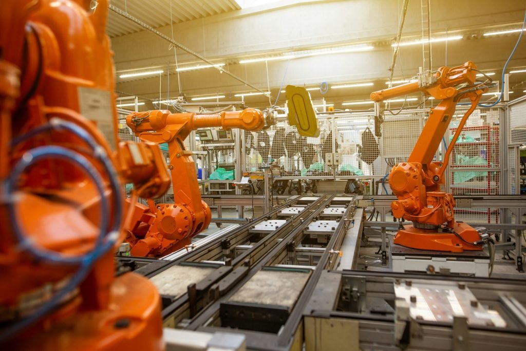 Orange industrial robotic arms working along a manufacturing production line