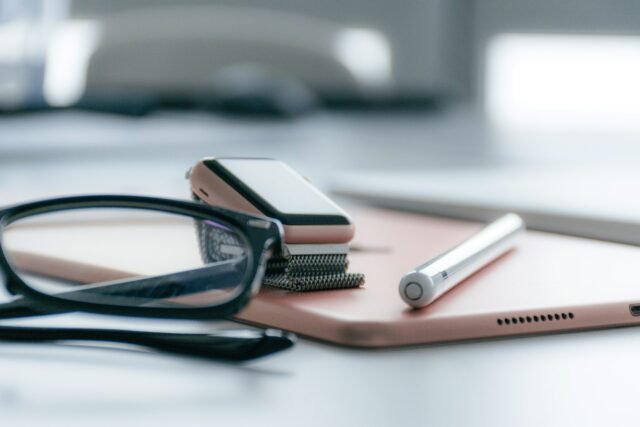 Eyeglasses, a smartwatch, a tablet and a stylus on a desk